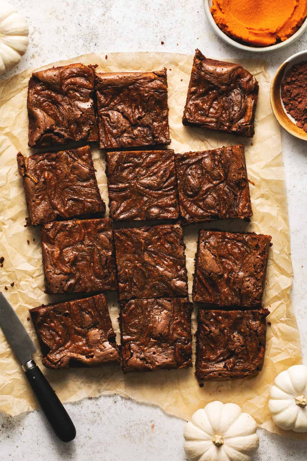 pumpkin brownies cut into squares on parchment paper