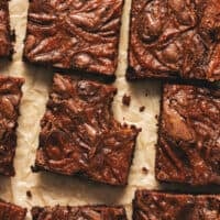 pumpkin brownie with bite taken on parchment with more brownies surrounding