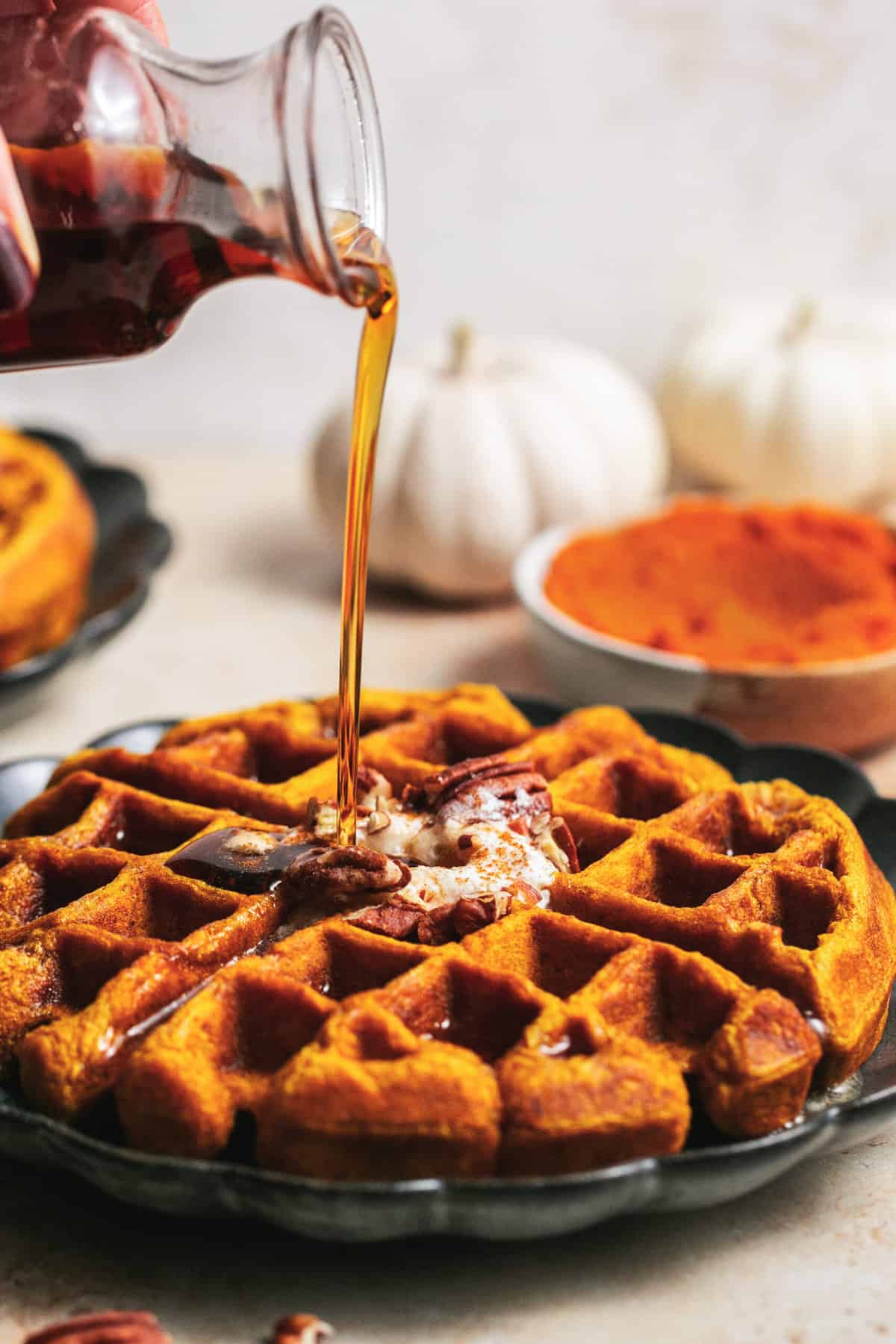 syrup pouring onto pumpkin waffle on plate