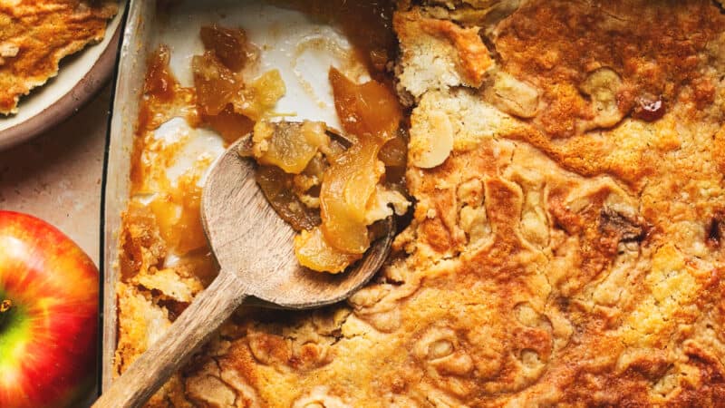 baked caramel apple dump cake in a baking pan with wooden serving spoon