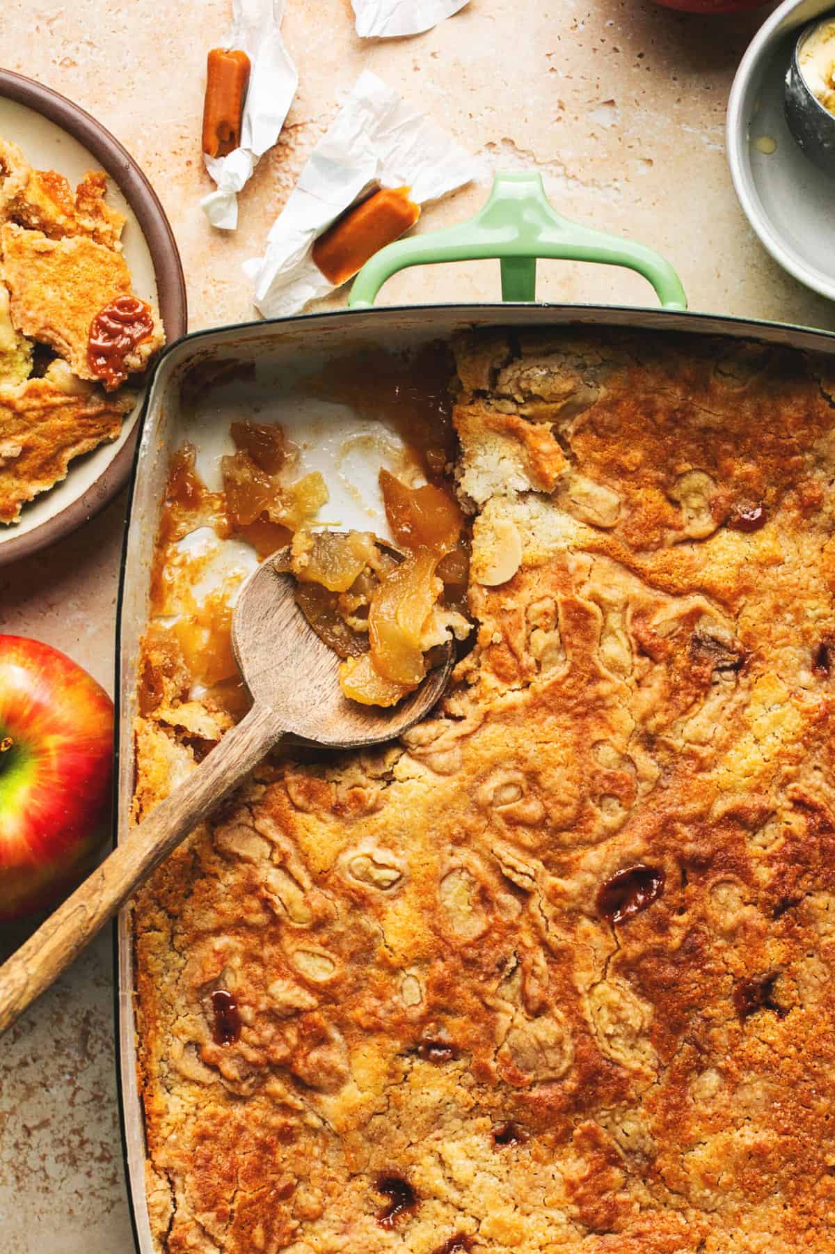 baked caramel apple dump cake in a baking pan with wooden serving spoon