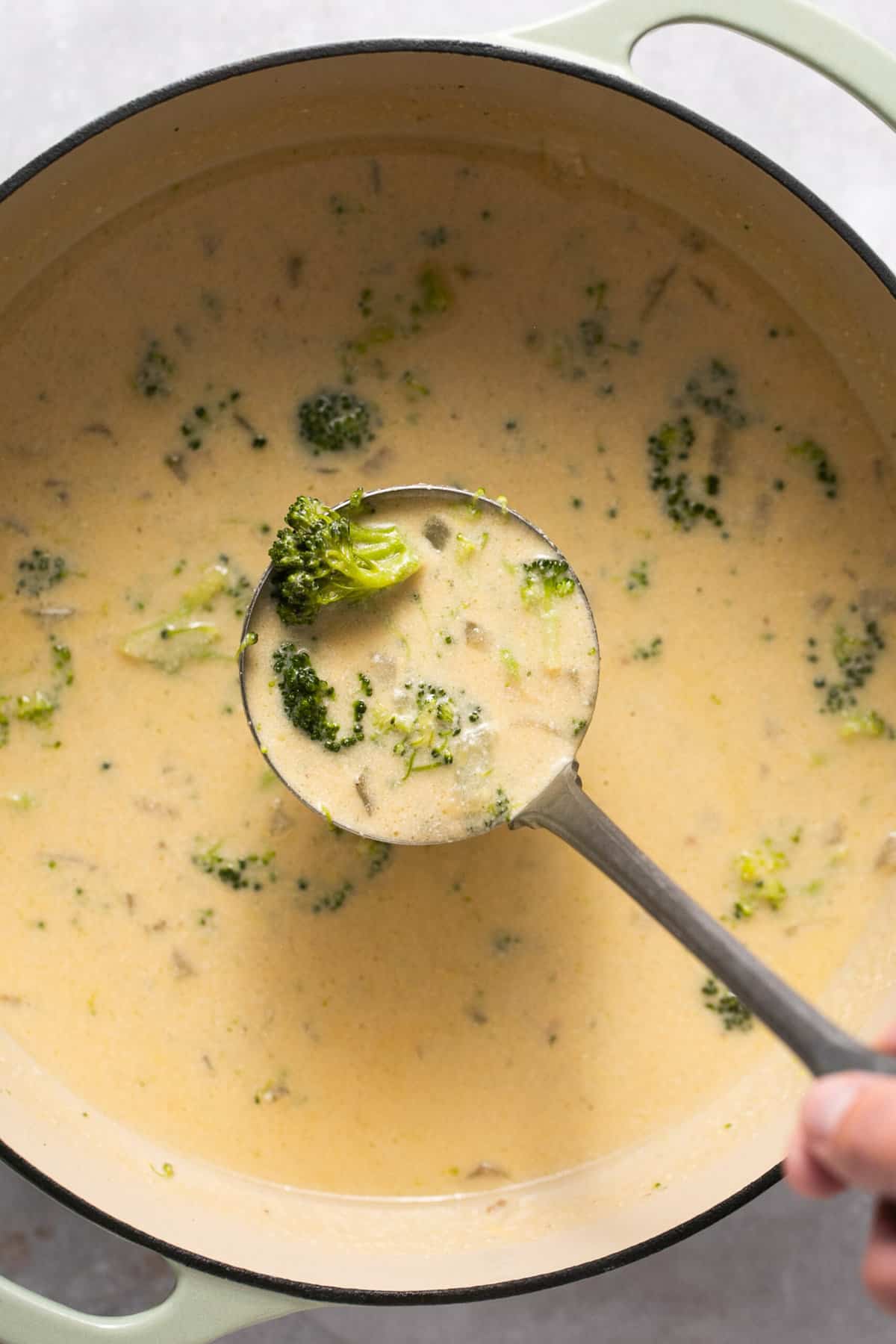 ladle scooping cheesy broccoli soup over pot