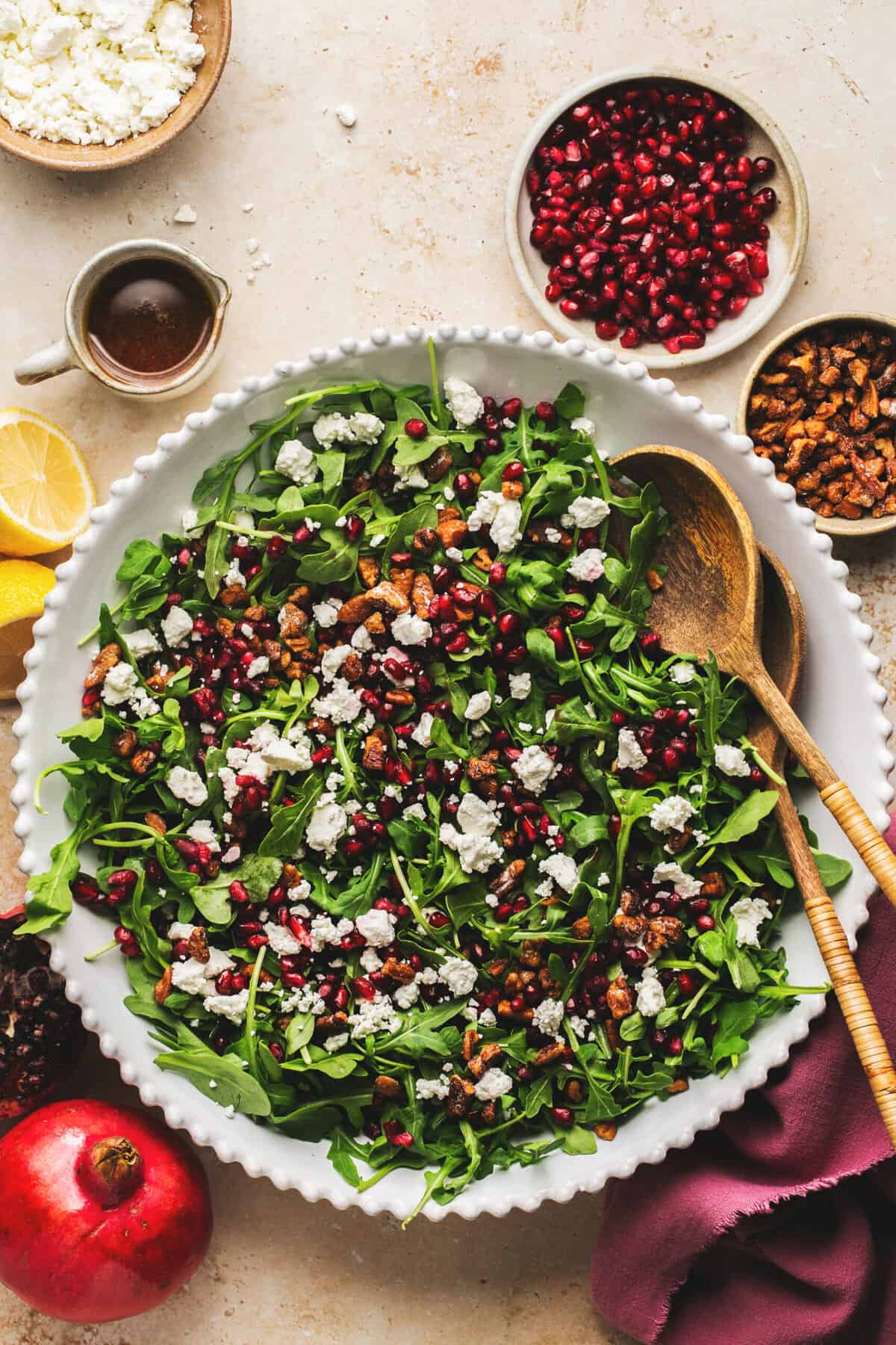 serving bowl of pomegranate salad with toppings in pinch bowls