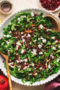 salad in bowl with greens, nuts, pomegranate, and crumbled cheese