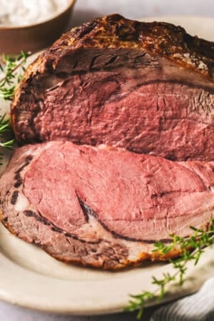 prime rib roast on a serving platter with fresh herbs