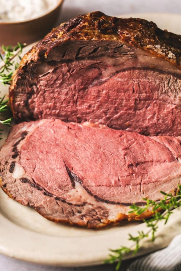 prime rib roast on a serving platter with fresh herbs