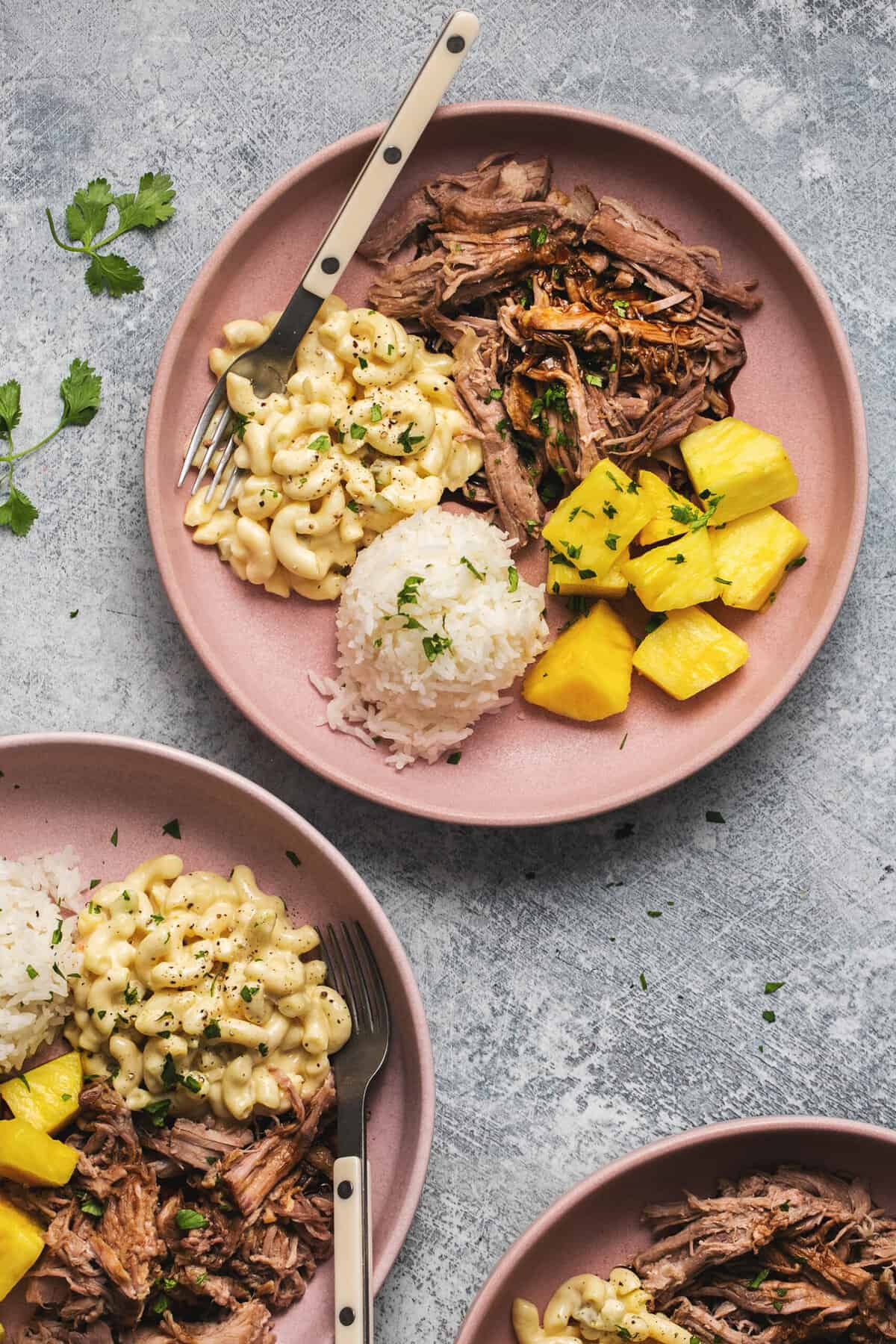 two plates of hawaiian pork with rice, pineapple, and macaroni