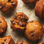 pumpkin muffin with one bite taken on table with more muffins
