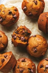 pumpkin muffin with one bite taken on table with more muffins