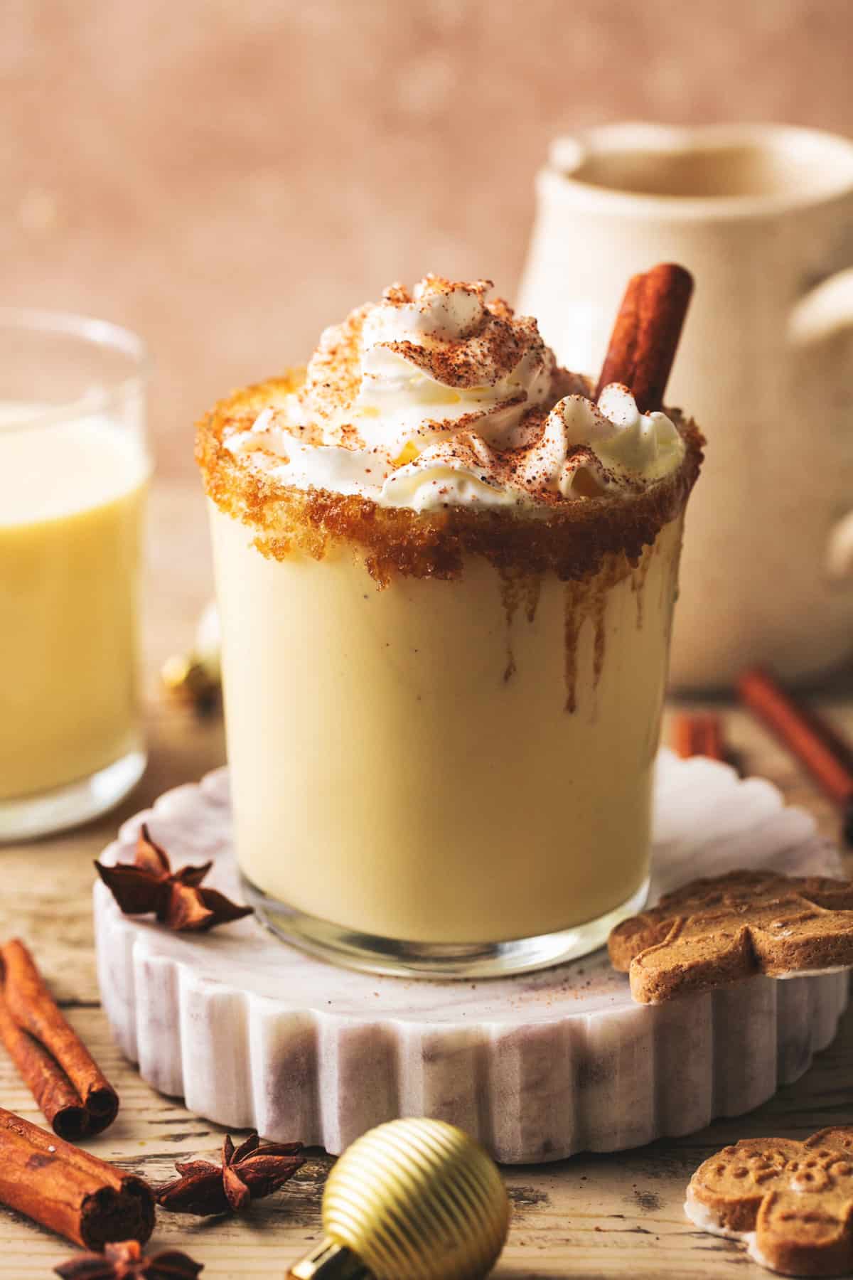 glass of eggnog with whipped cream and cinnamon stick