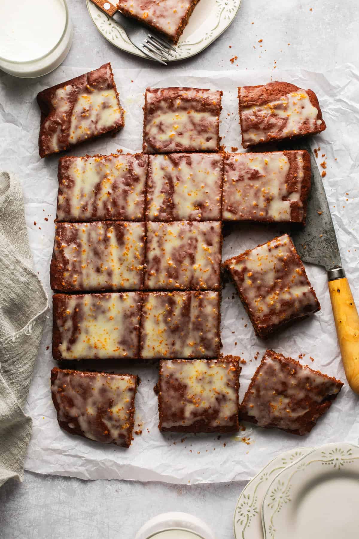 gingerbread cake with orange glaze cut into squares with knife on table