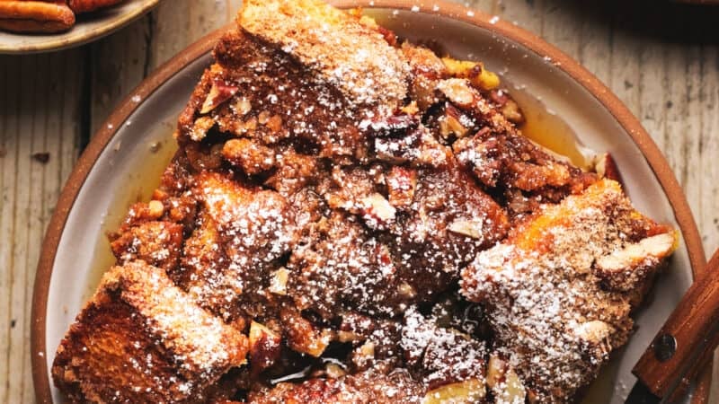 single serving of french toast casserole on plate with pecans in dish