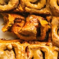 up close view of cinnamon rolls in pan with one. partly unrolled showing filling