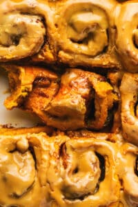 up close view of cinnamon rolls in pan with one. partly unrolled showing filling