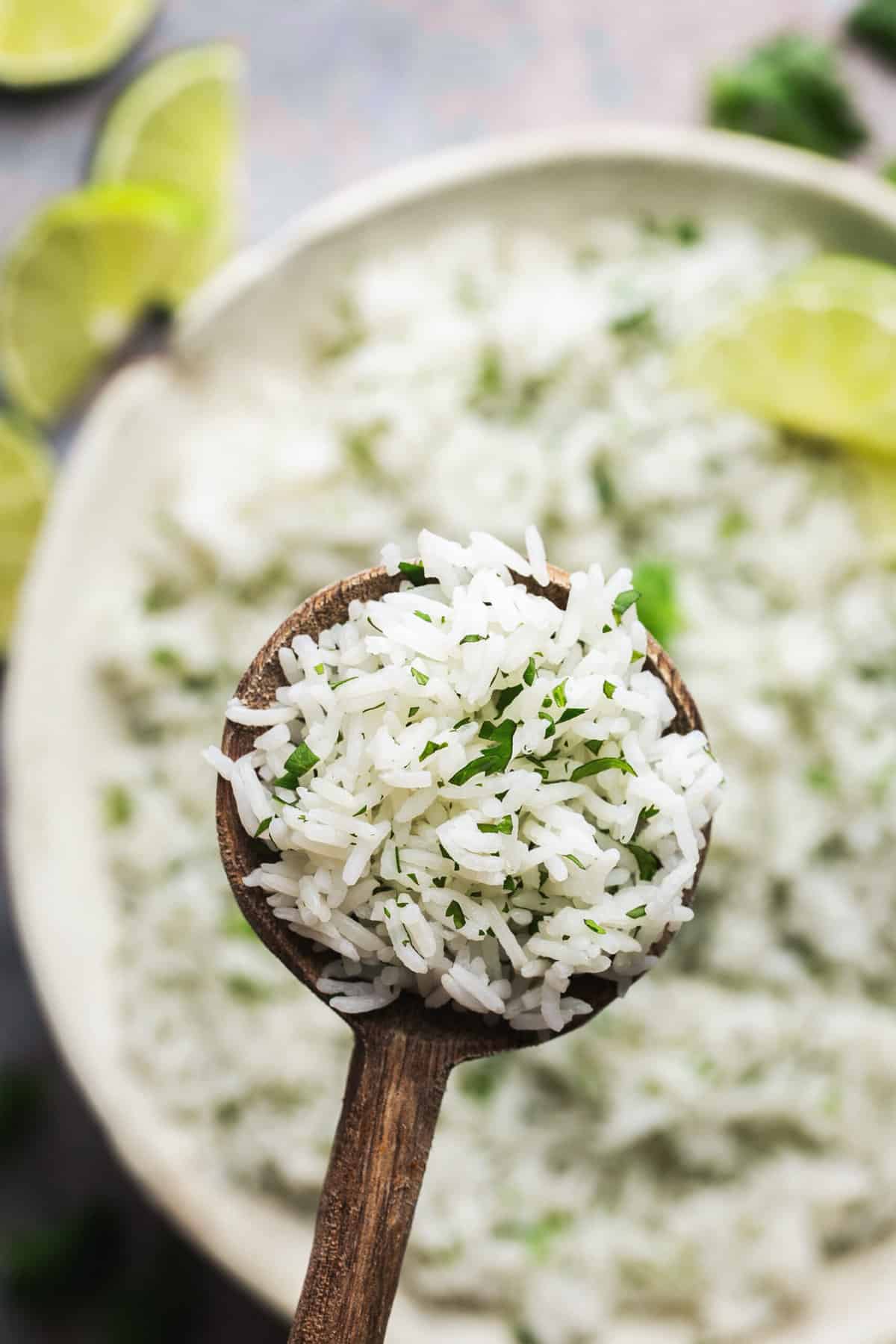 wooden spoon scooping rice with cilantro above bowl