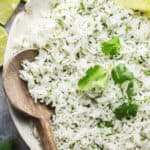 half of a bowl of cilantro lime rice with wooden serving spoon
