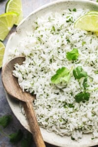 half of a bowl of cilantro lime rice with wooden serving spoon