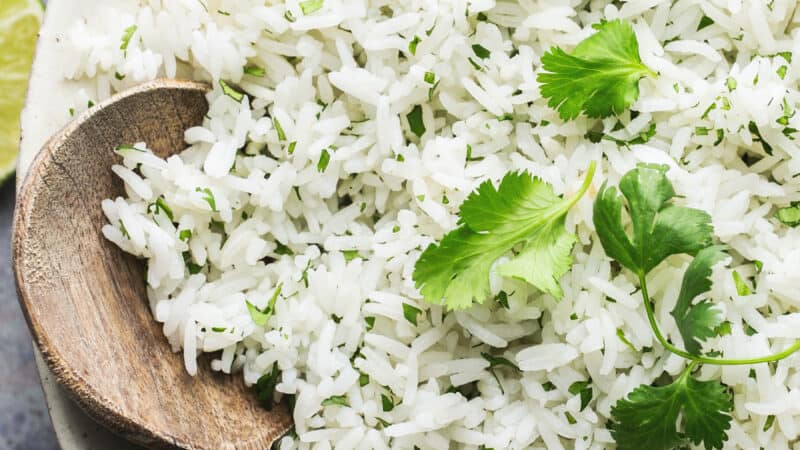 half of a bowl of cilantro lime rice with wooden serving spoon