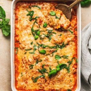 overhead view of baked ravioli in casserole dish on table with wooden serving spoon