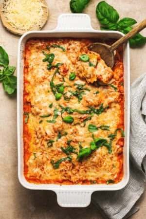 overhead view of baked ravioli in casserole dish on table with wooden serving spoon