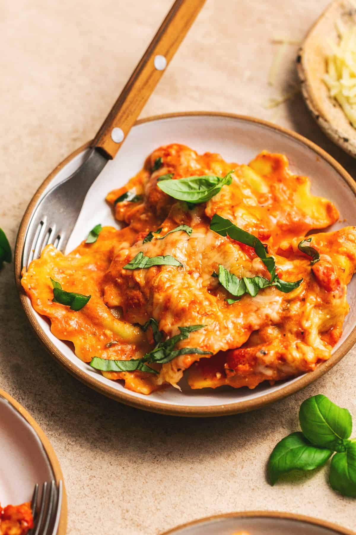 ravioli in red pepper sauce in a bowl with a fork and fresh basil