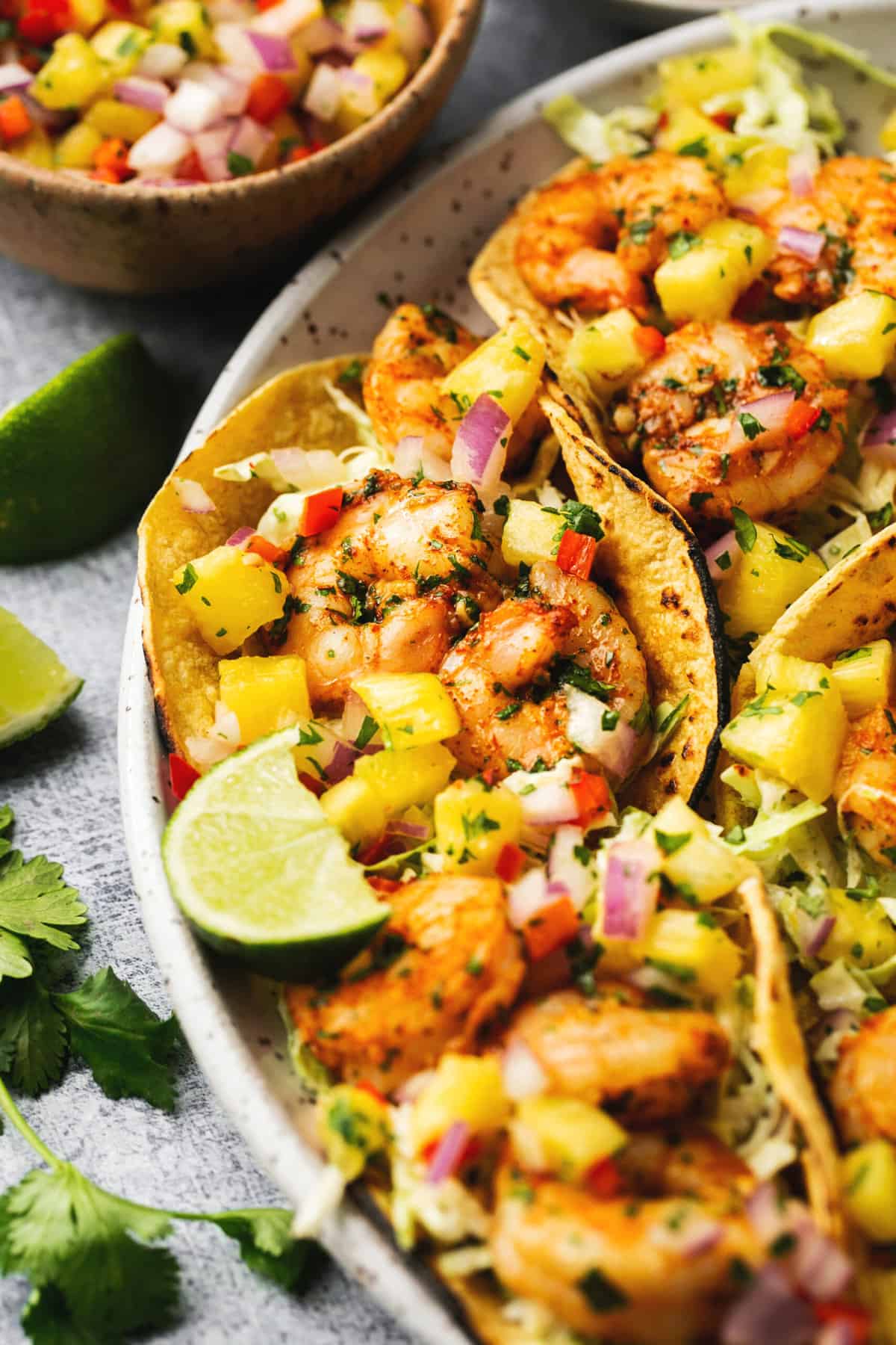 shrimp tacos with pineapple and lime wedges on platter