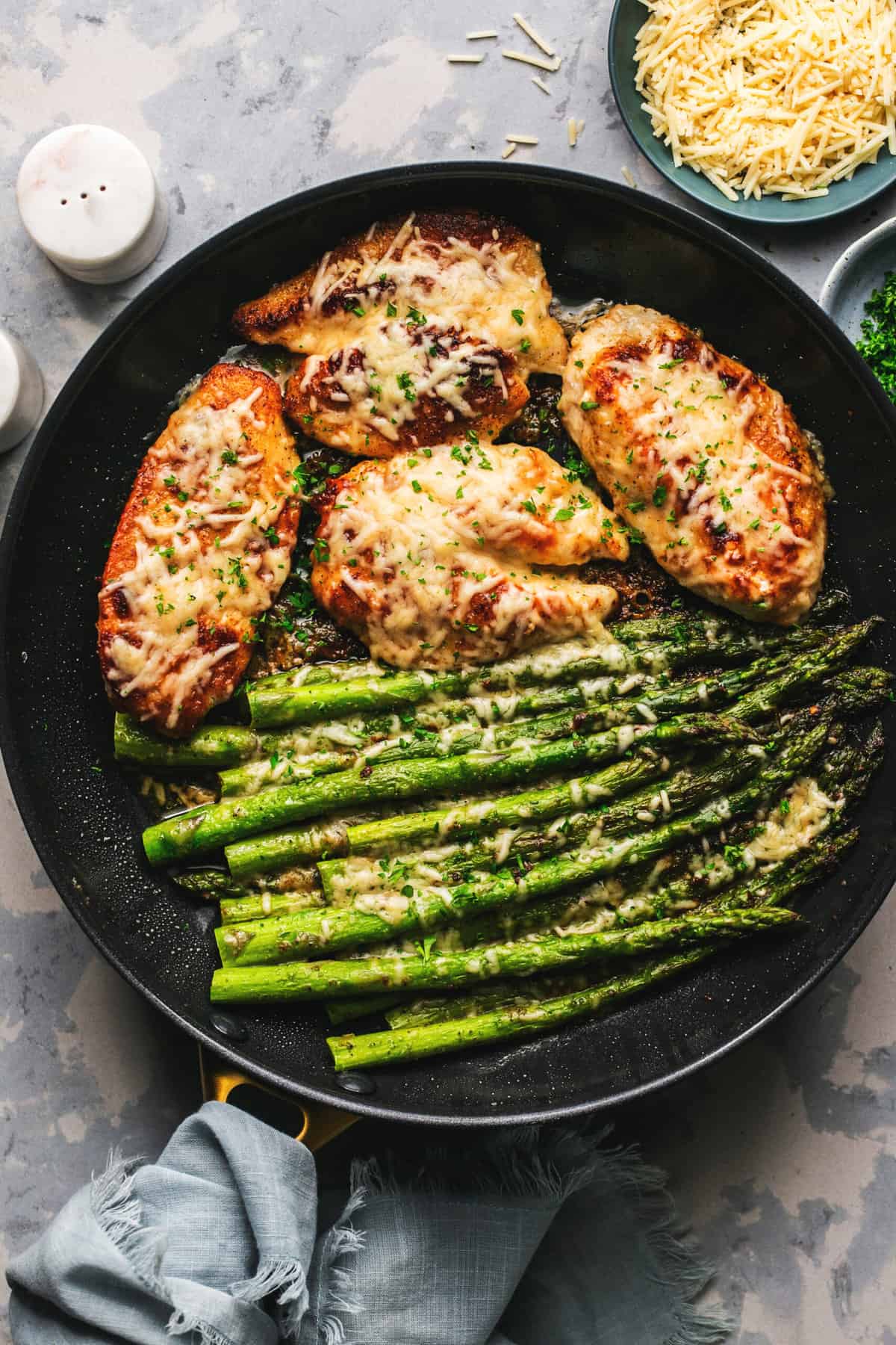 skillet with browned chicken breasts and sauteed asparagus