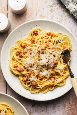 one plate of spaghetti carbonara noodles with pancetta and parmesan cheese with fork in dish
