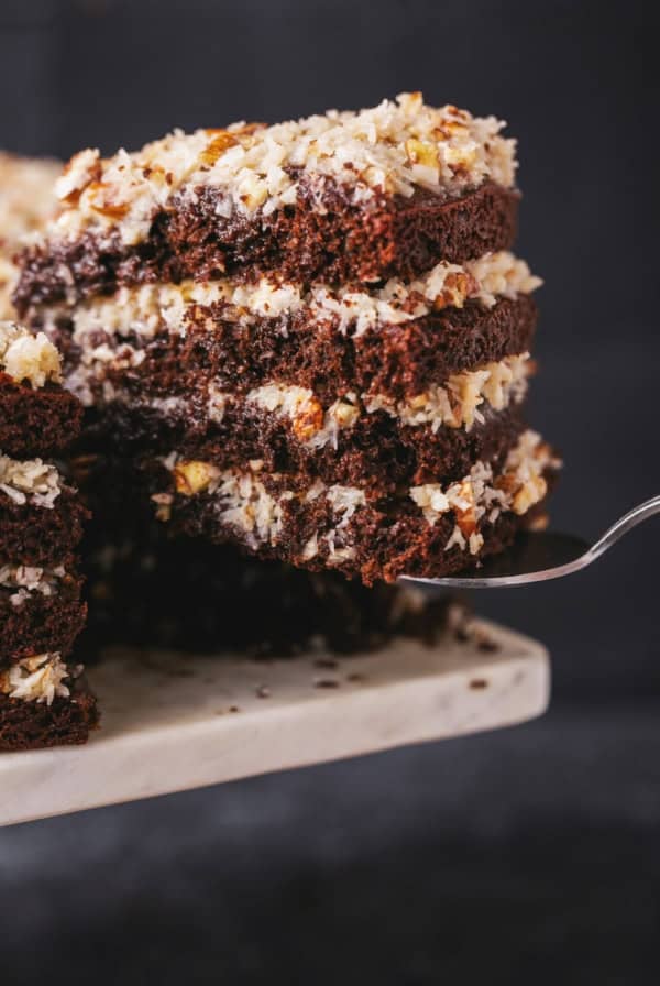 cake server lifting slice of german chocolate cake from cake stand