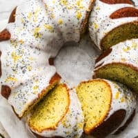 overhead view of sliced bundt cake with glaze and poppy seed garnish