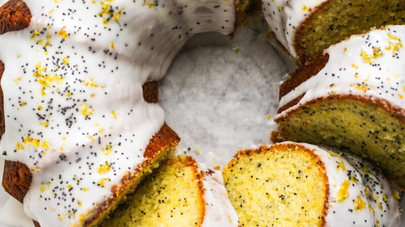 overhead view of sliced bundt cake with glaze and poppy seed garnish
