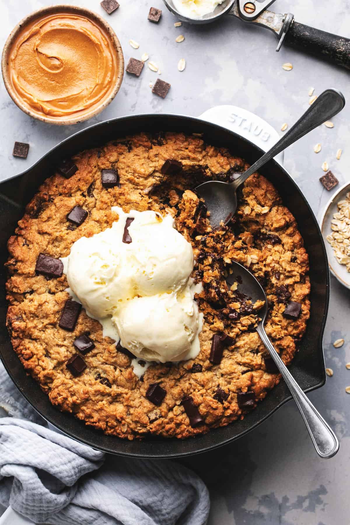 baked skillet cookie with two spoons and ice cream