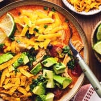 chicken tortilla soup in a bowl with a spoon and taco toppings