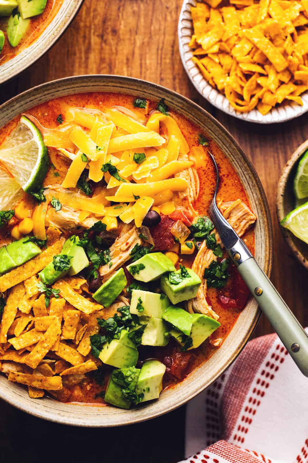 chicken tortilla soup in a bowl with a spoon and taco toppings