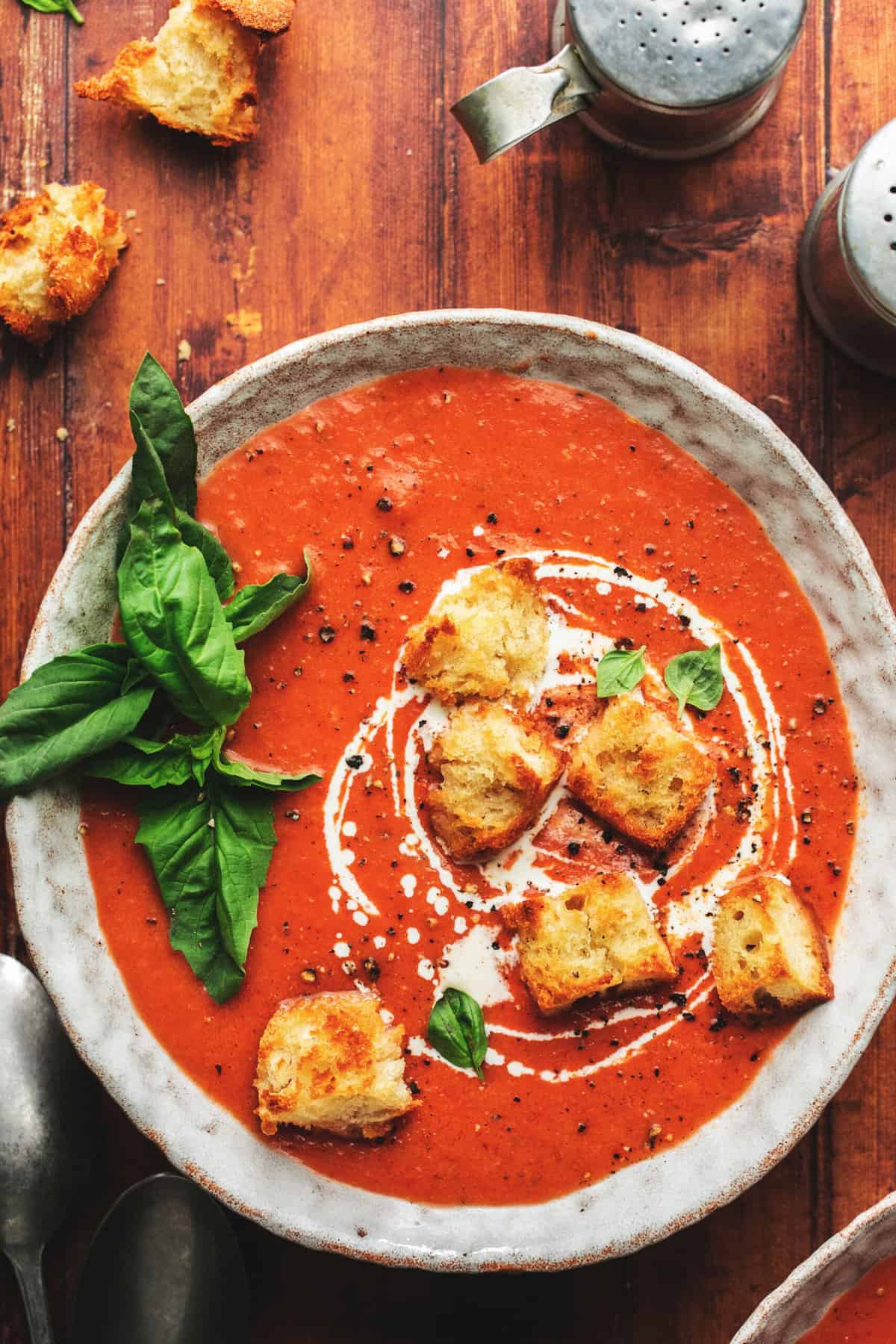 overhead view of bowl of tomato soup with croutons and fresh basil