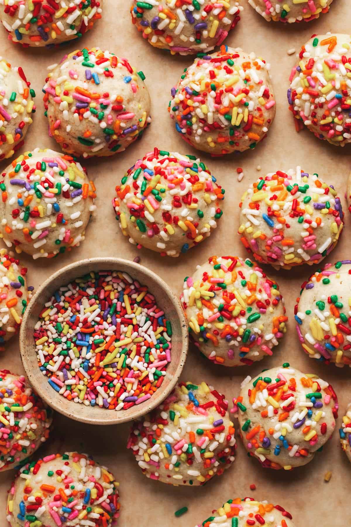 cookies rolled in colorful sprinkles with extra sprinkles in pinch bowl