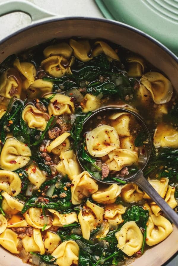 ladle scooping tortellini and sausage soup