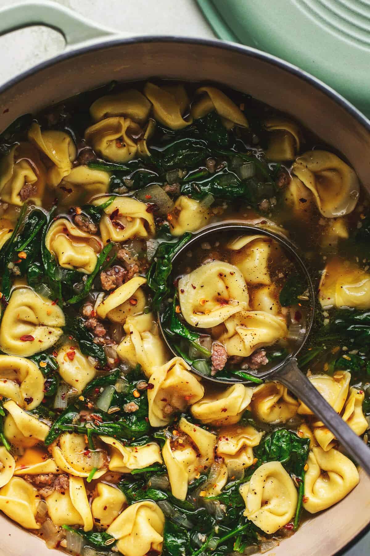 ladle scooping tortellini and sausage soup