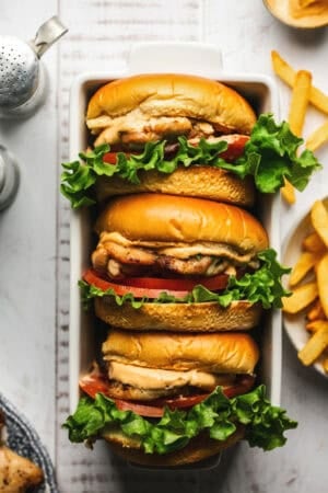 three sandwiches with chicken thighs stacked in a bread pan