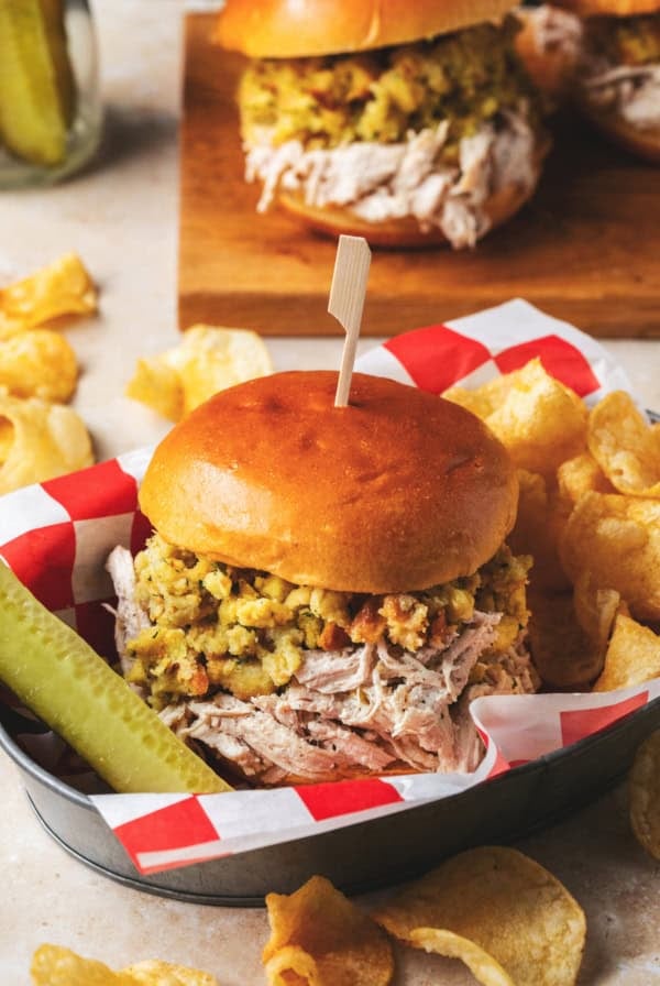 shredded chicken and stuffing sandwich with pickle and chips in basket
