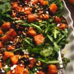 arugula salad on platter with roasted butternut squash, cranberries, and seeds