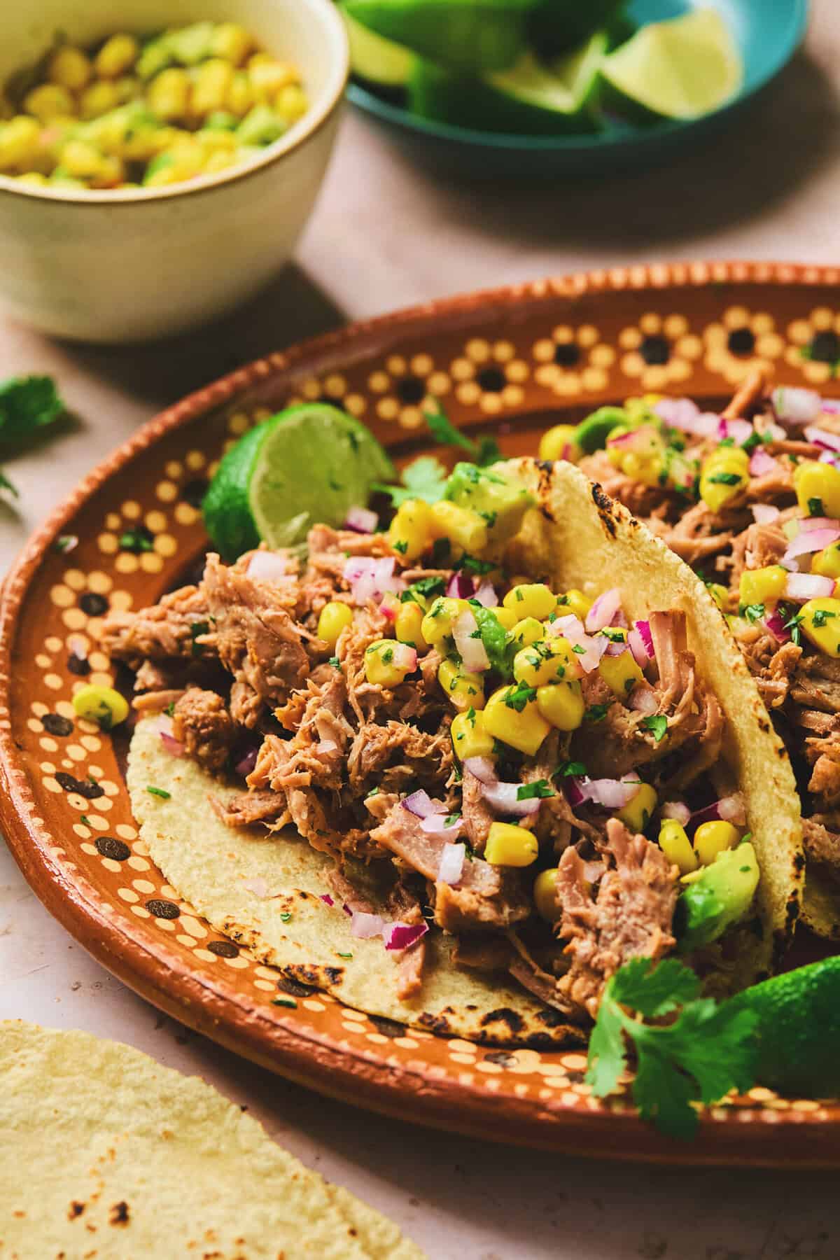pork tacos with corn salsa and lime garnish on platter.