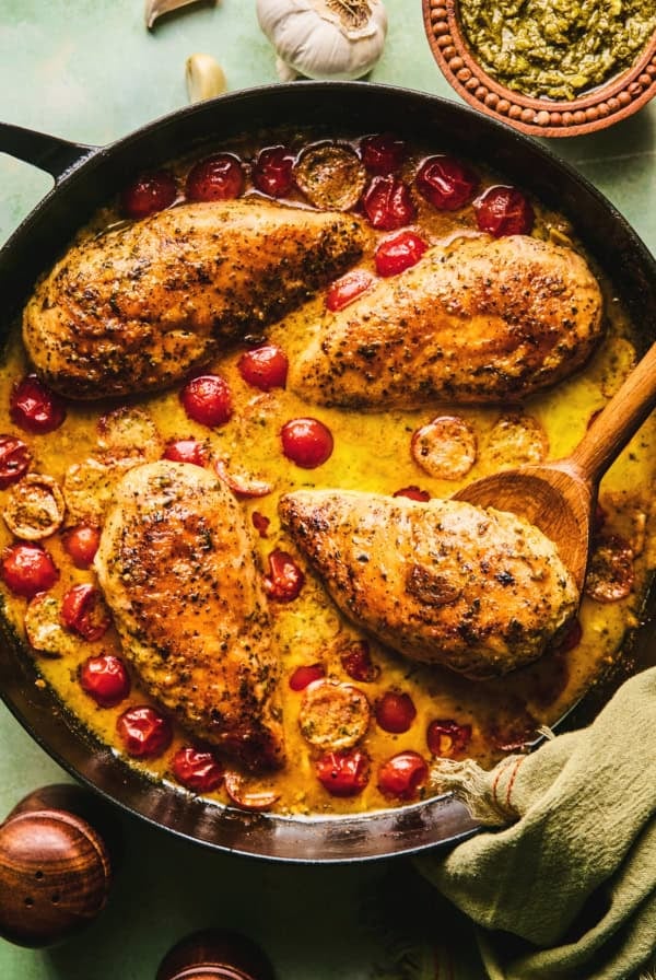 chicken in tomato and cream sauce in skillet with wooden serving spoon