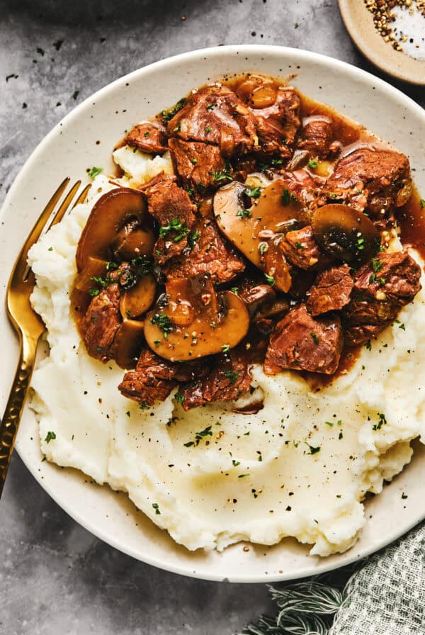 Overhead close up of instant pot beef tips and mashed potatoes with a fork on a plate.