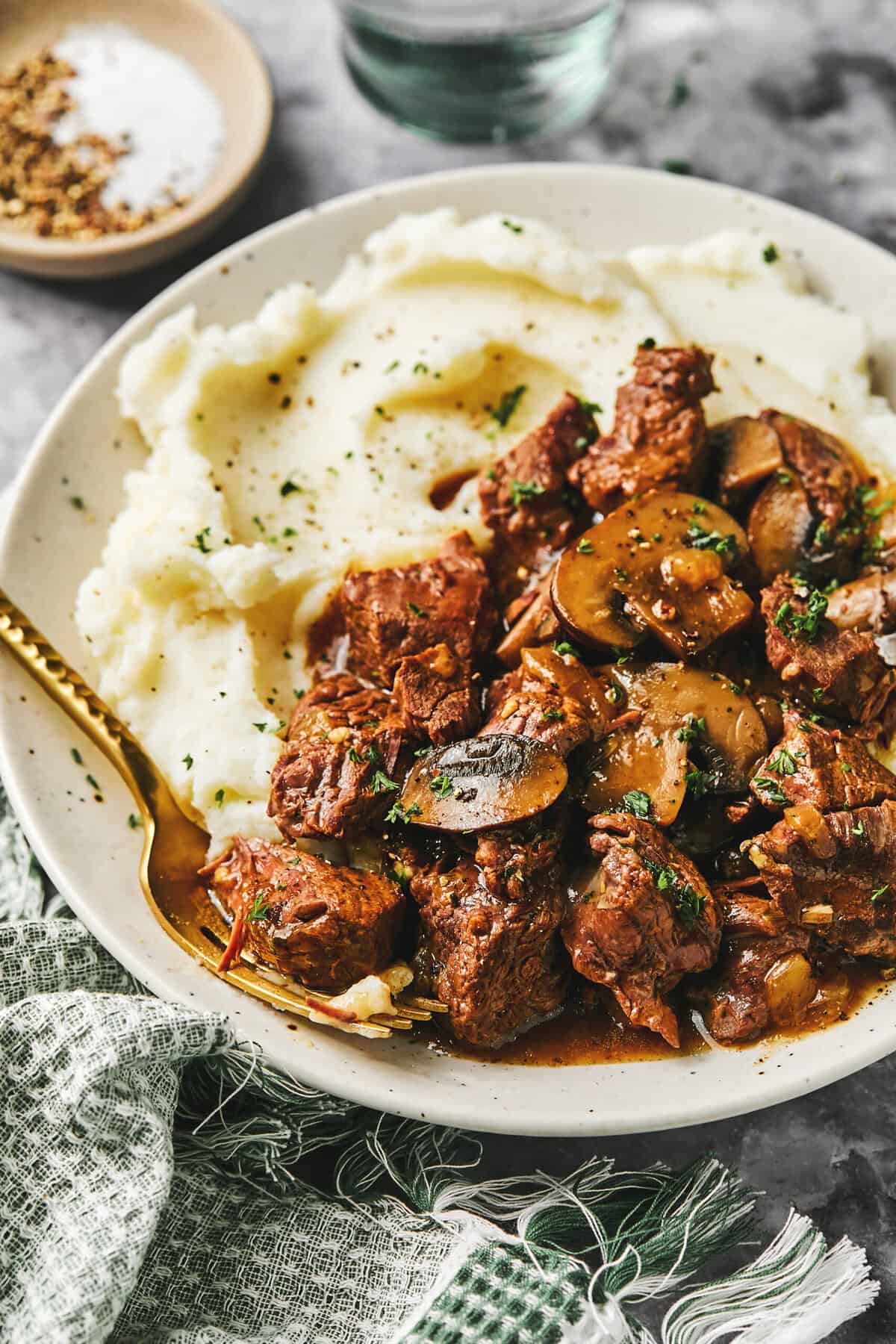 Close up of instant pot beef tips and mashed potatoes with a fork on a plate.