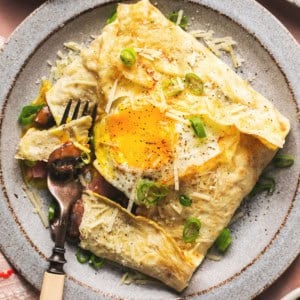 crepe filled with egg and ham on plate with fork