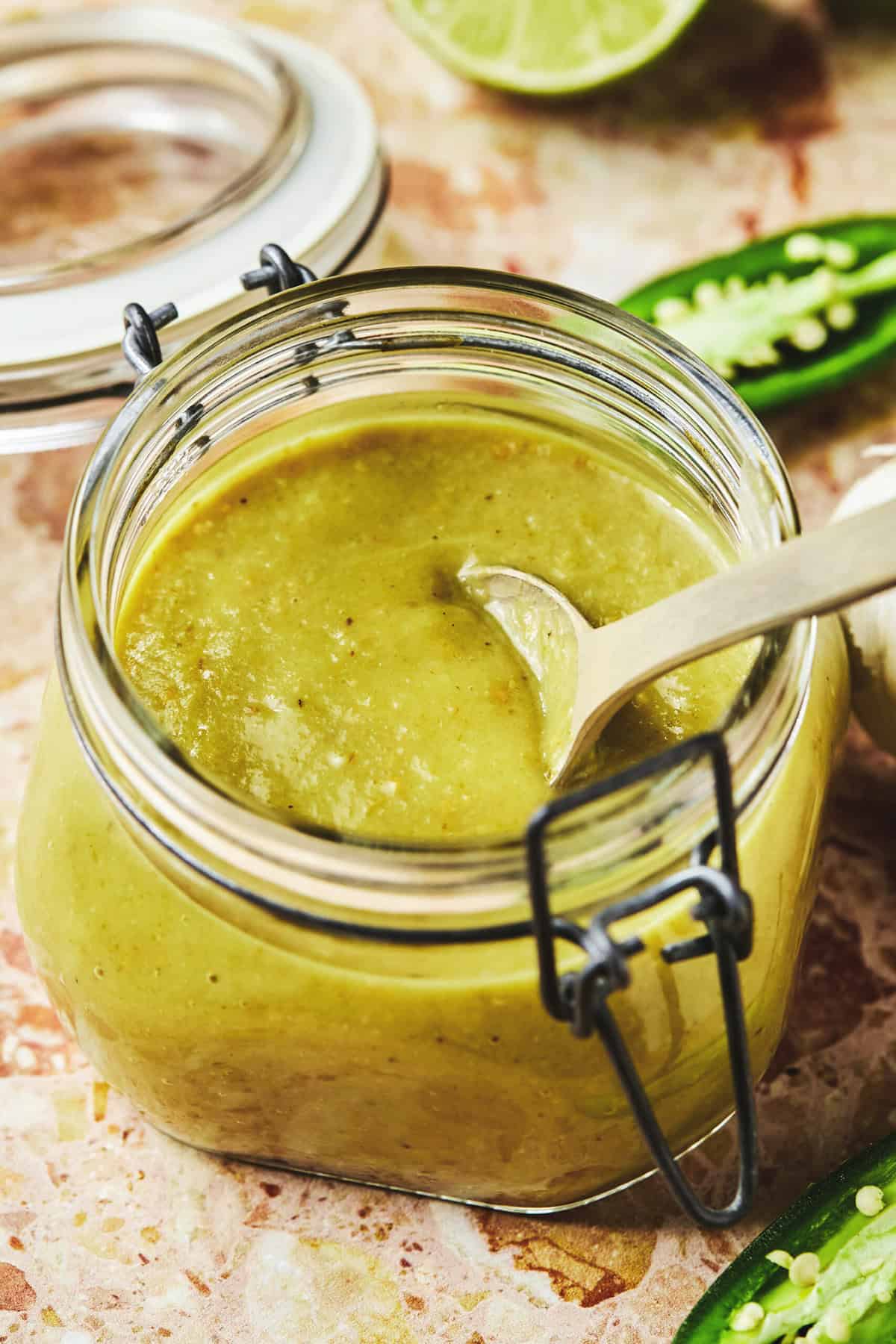Šaukštas panardinkite į žalią enchilada padažą stiklainyje