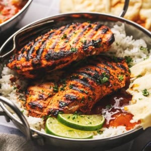 grilled tandoori chicken over rice with lime wedges, naan, and chutney