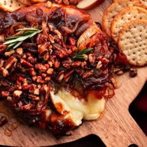 baked brie appetizer with nuts and fig jam served with apples and crackers.