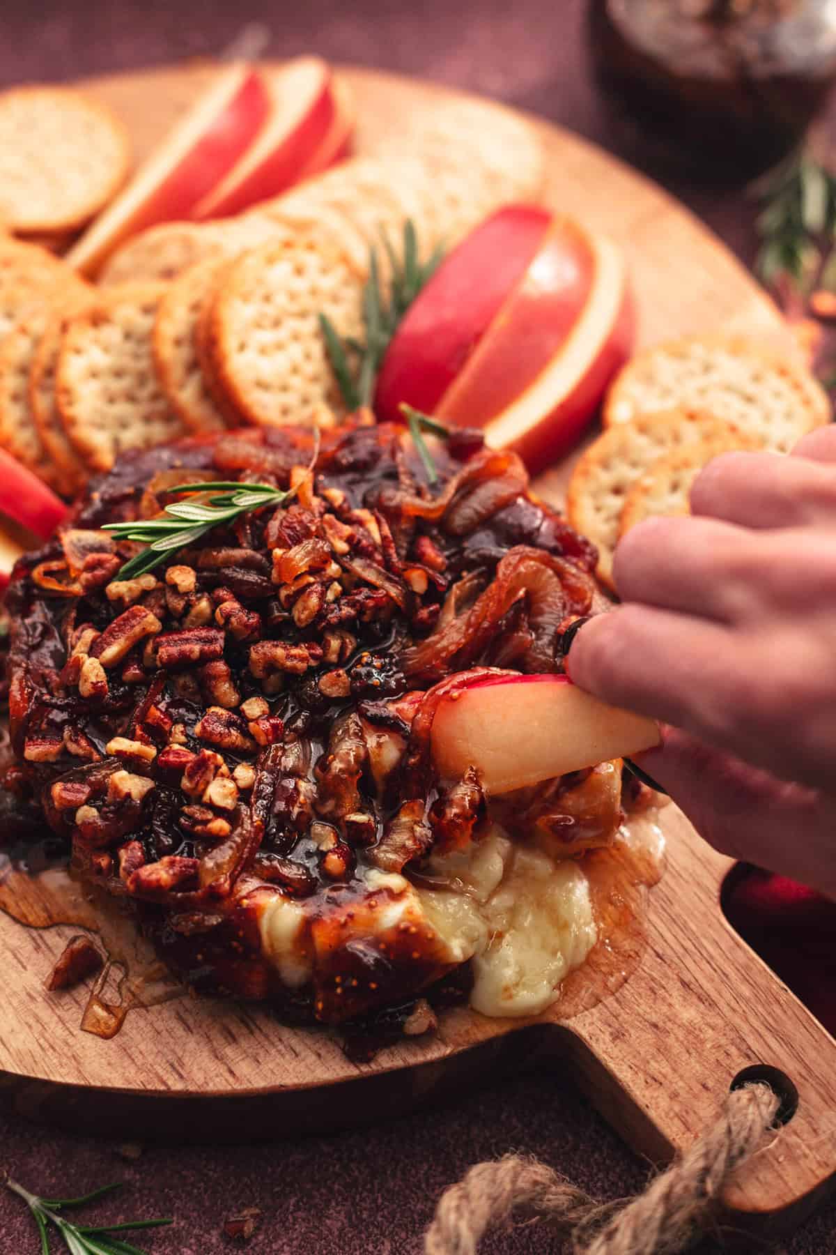 baked brie appetizer with nuts and fig jam served with apples and crackers.